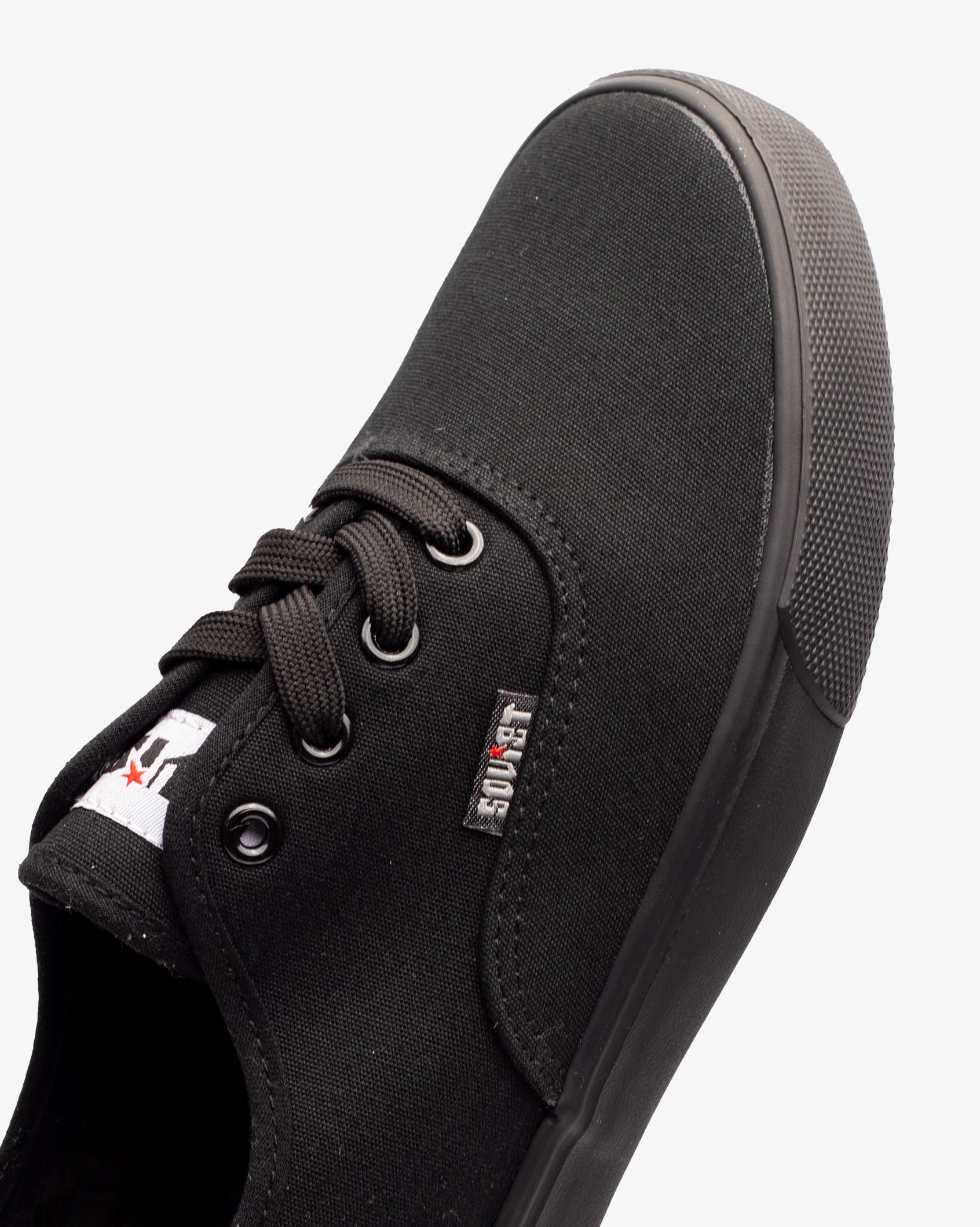Black low-top canvas sneaker with lace-up closure and fabric tongue label