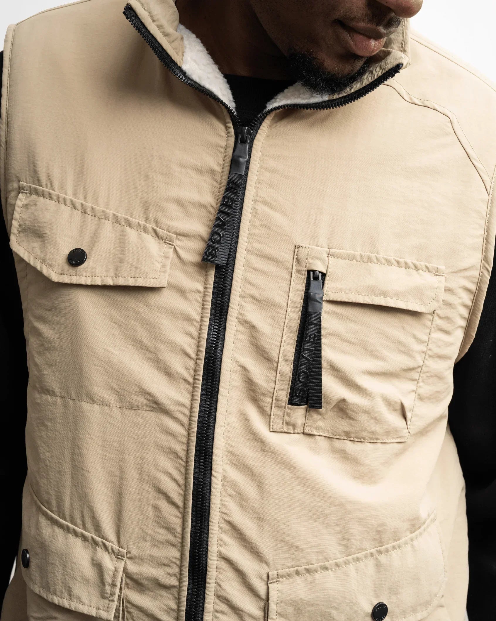 Men's stone fashion gilet with black zip, stand collar, chest pockets, flap details