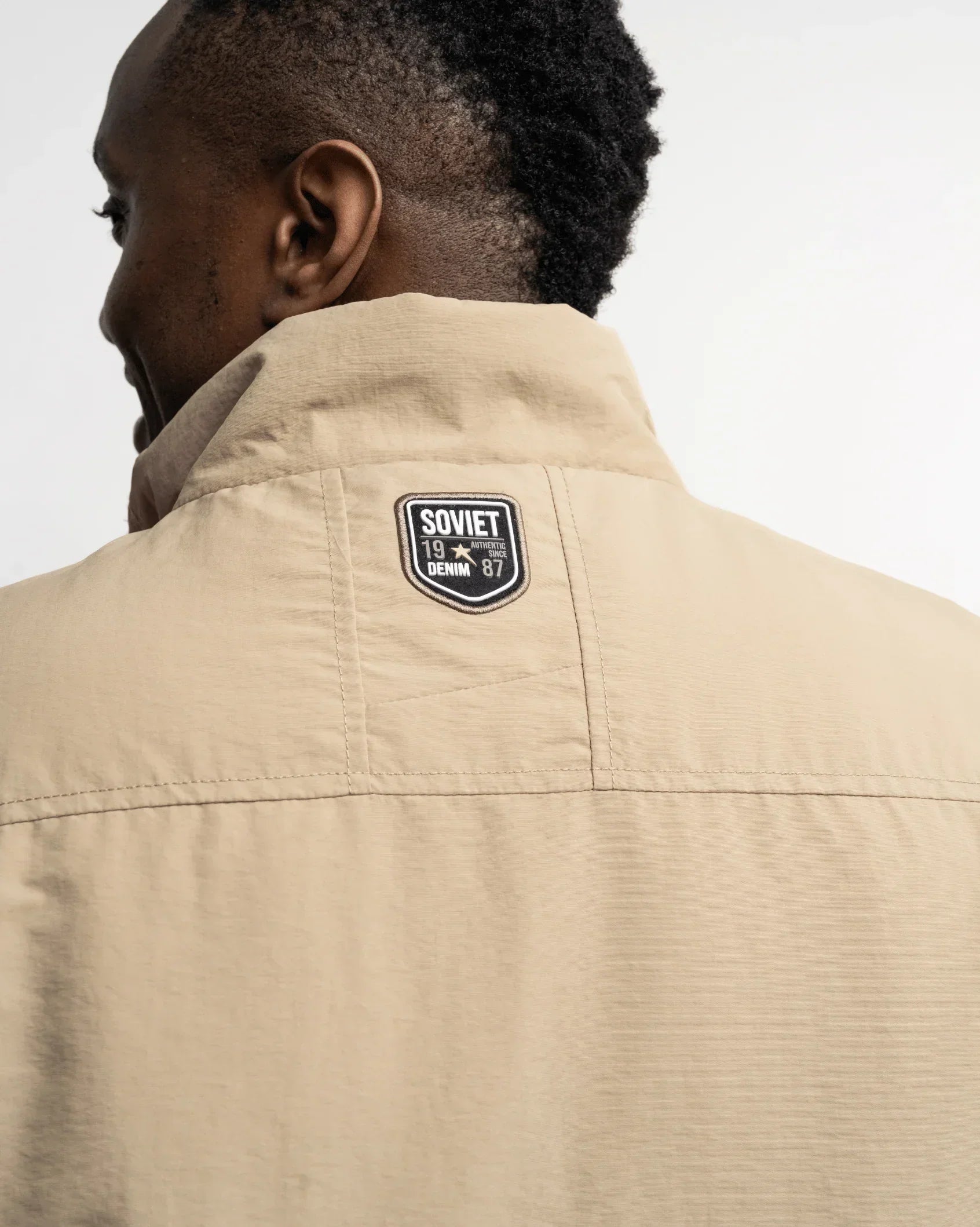 Men's stone fashion gilet back view with neck patch and stand collar