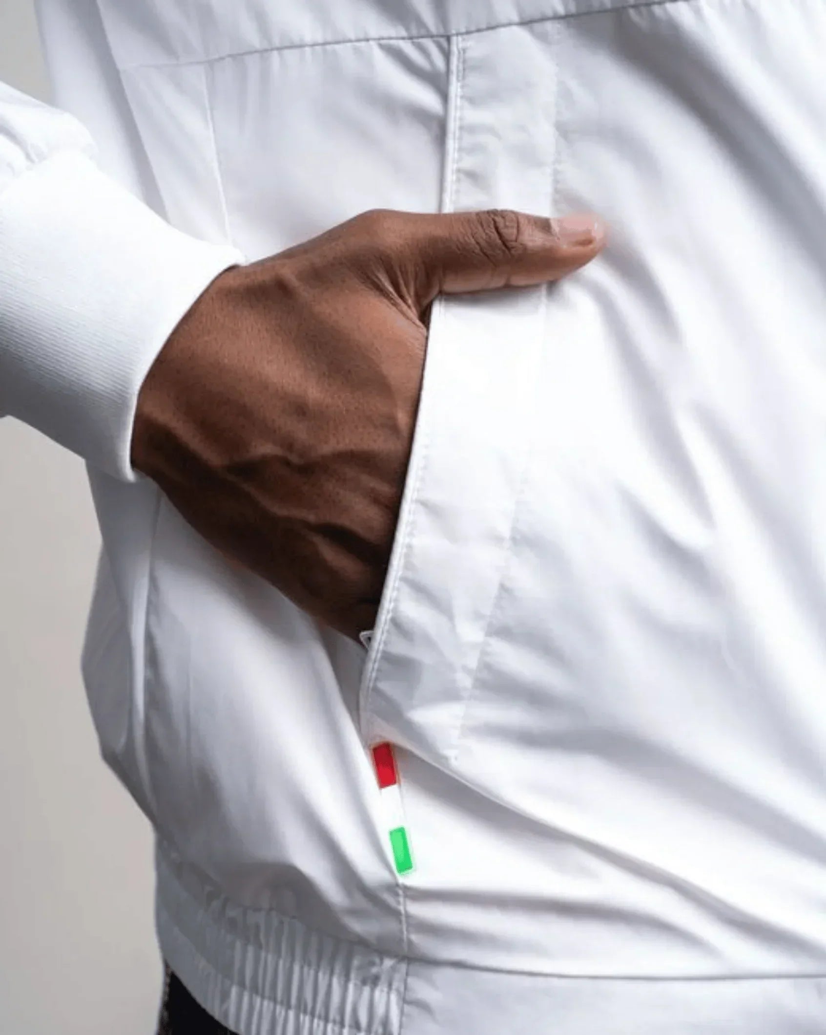 White lightweight jacket close-up with zipper, side pocket, and elastic hem