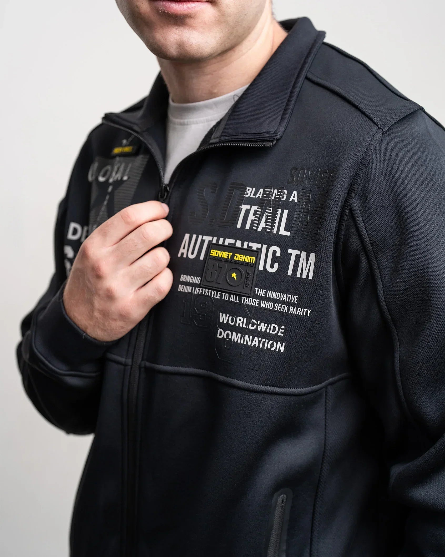 Black zip-up jacket with chest graphic print and stand collar, close-up